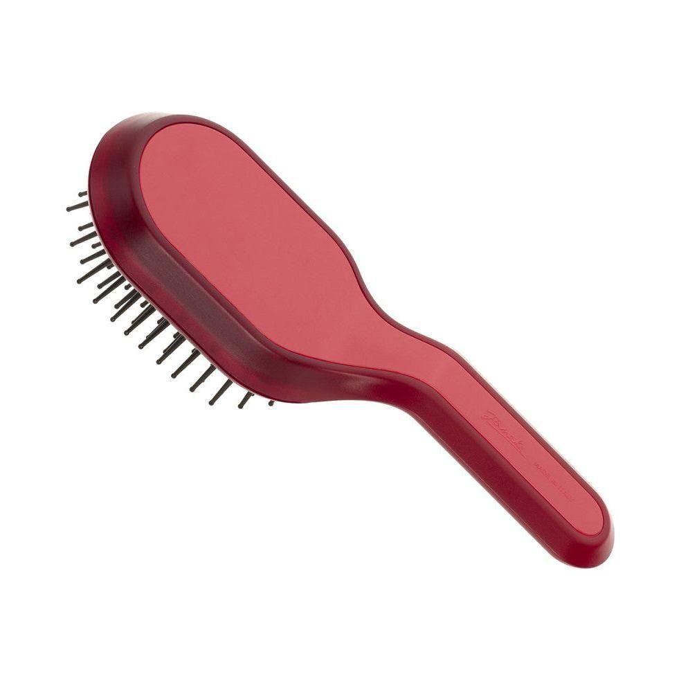 Spazzola per capelli magenta con manico. Testina rettangolare con setole nere. Forma arrotondata.