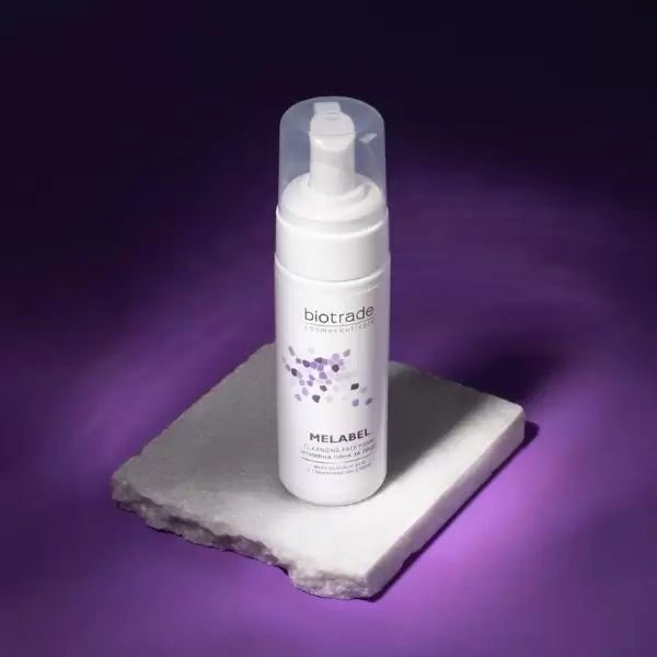 Schiuma detergente Biotrade Melabel bianca su base. Tappo trasparente. Sfondo viola.