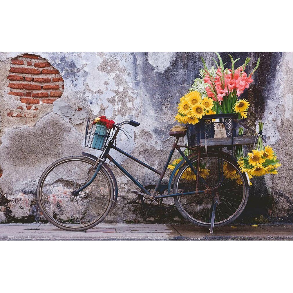 Bicicletta con fiori davanti a un muro. Cesto e portapacchi con fiori. Sfondo: muro con mattoni.