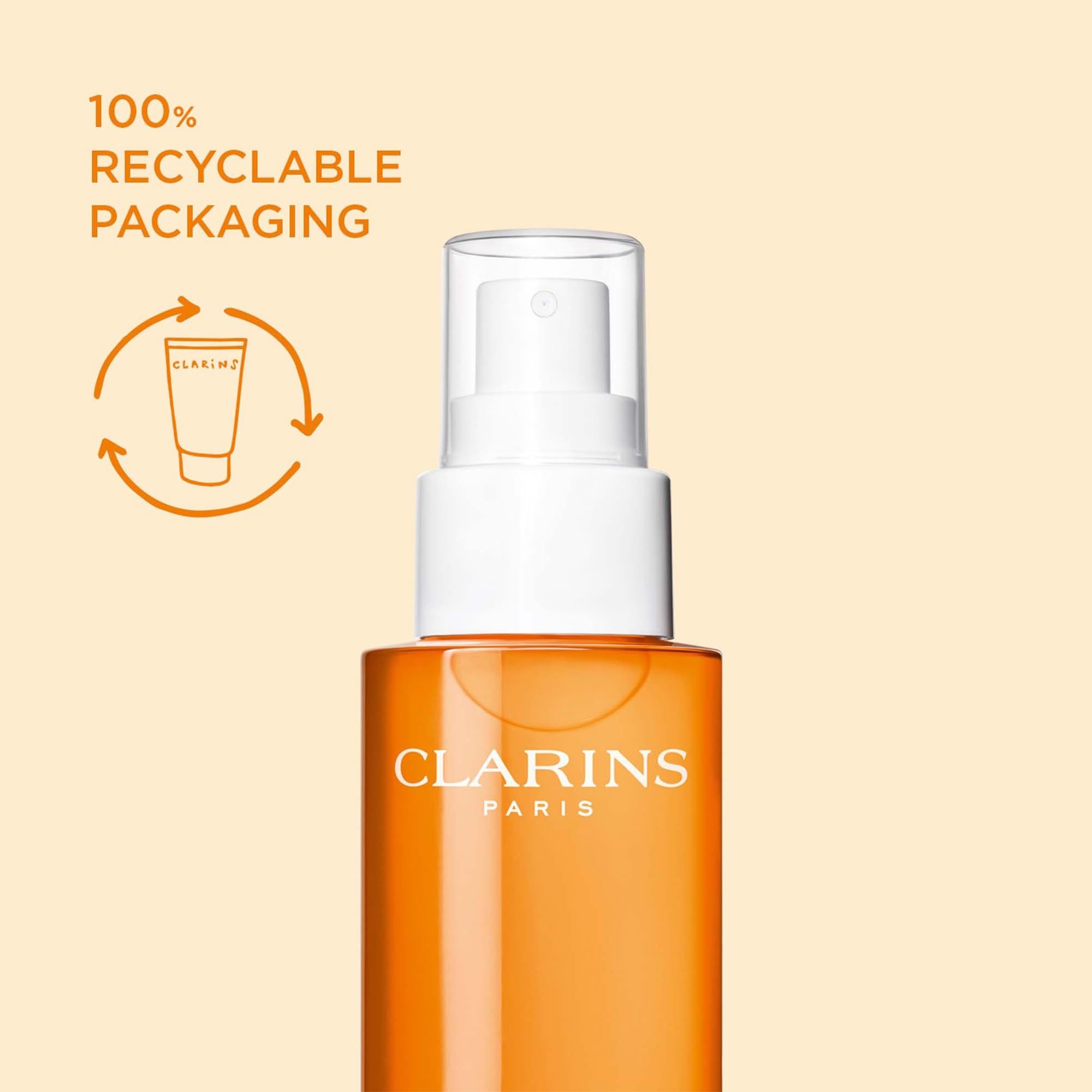 Flacone spray arancione con erogatore bianco. Testo: Clarins Paris. Scritta: Imballaggio riciclabile al 100%.
