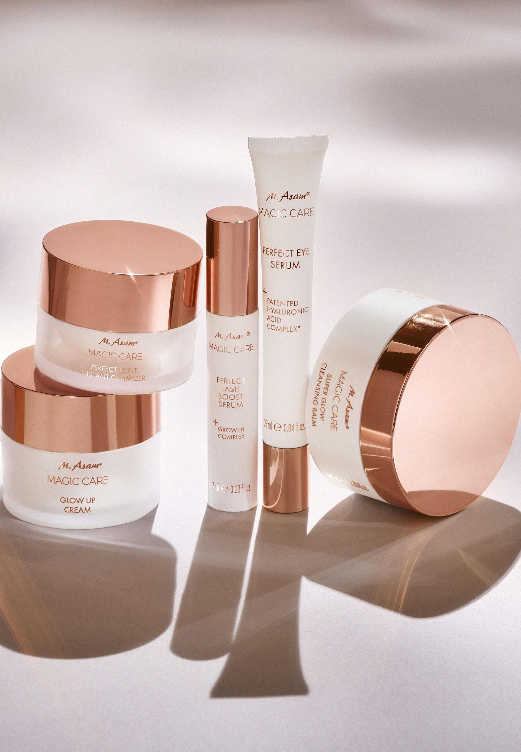 Set di prodotti: vasetti di crema, siero, crema occhi. Testo: M. Asam MAGIC CARE. Coperchi color oro rosa.