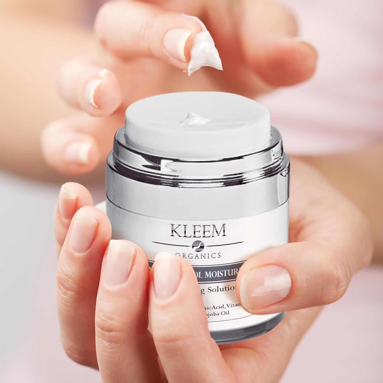 Mani che tengono il prodotto. Testo: Kleem Organics, Advanced Retinol Moisturizer. Crema prelevata.