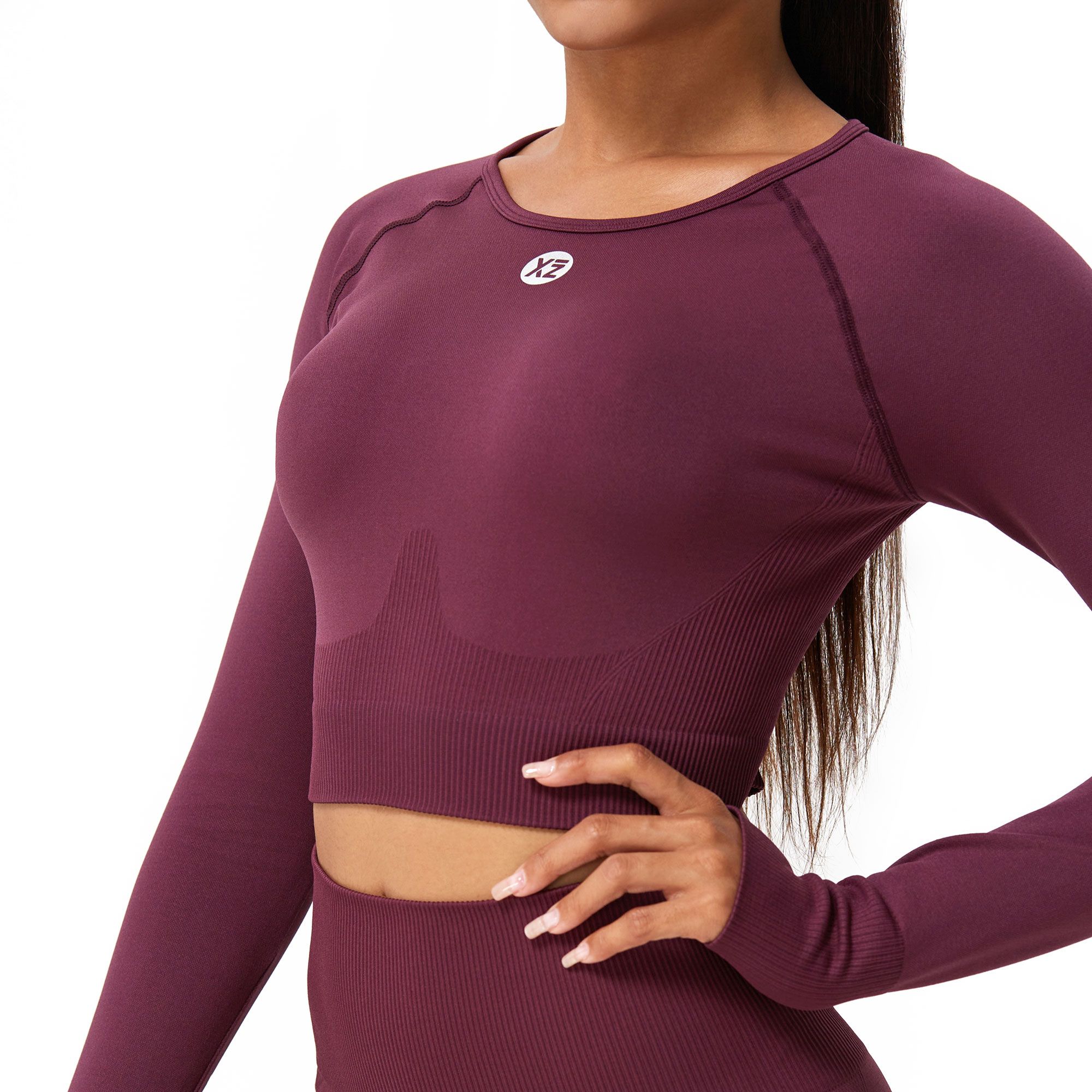 Crop top bordeaux a maniche lunghe aderente, con scollo rotondo e logo discreto sul petto.