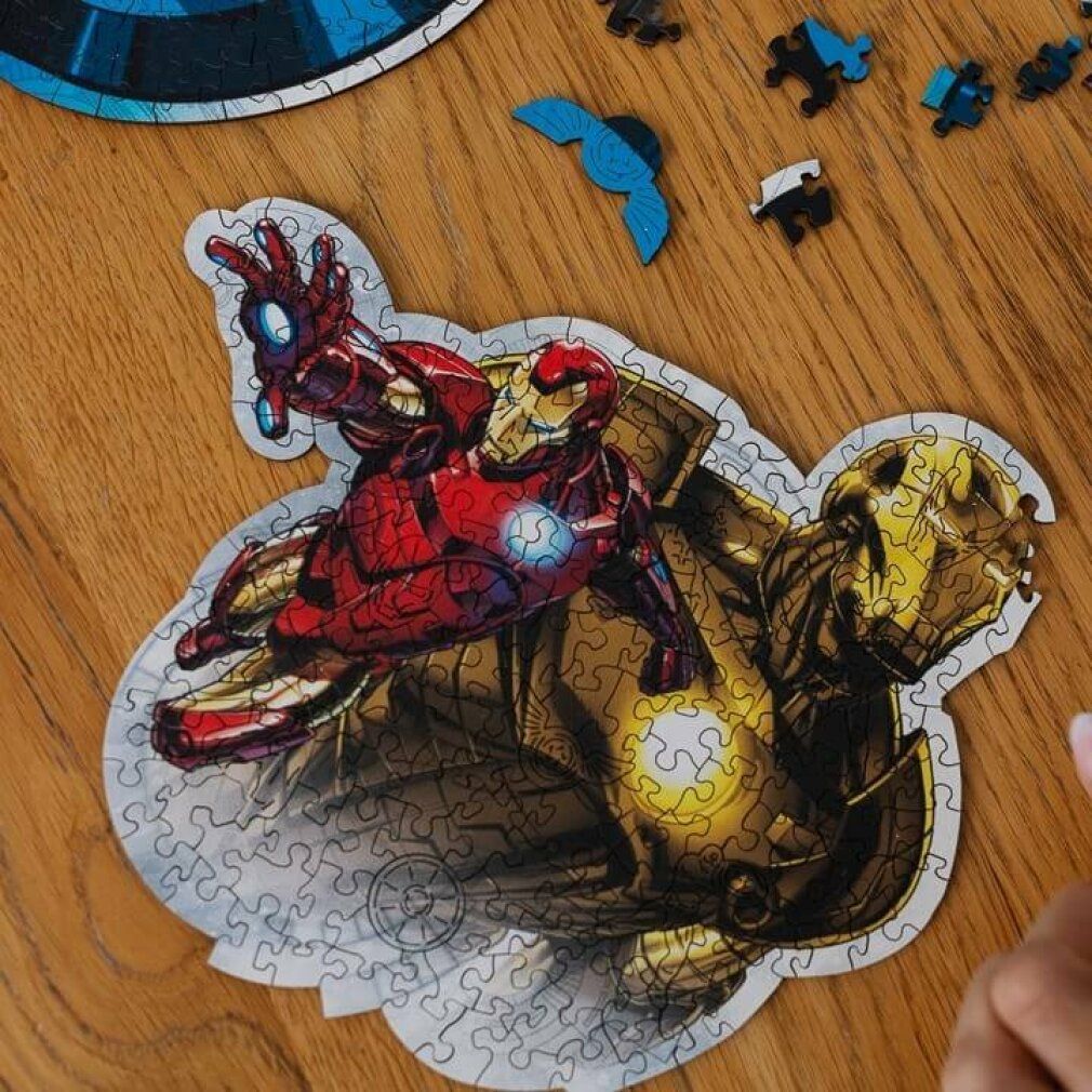 Puzzle parzialmente assemblato con motivo di Iron Man. Singoli pezzi del puzzle accanto. Superficie in legno come sfondo.
