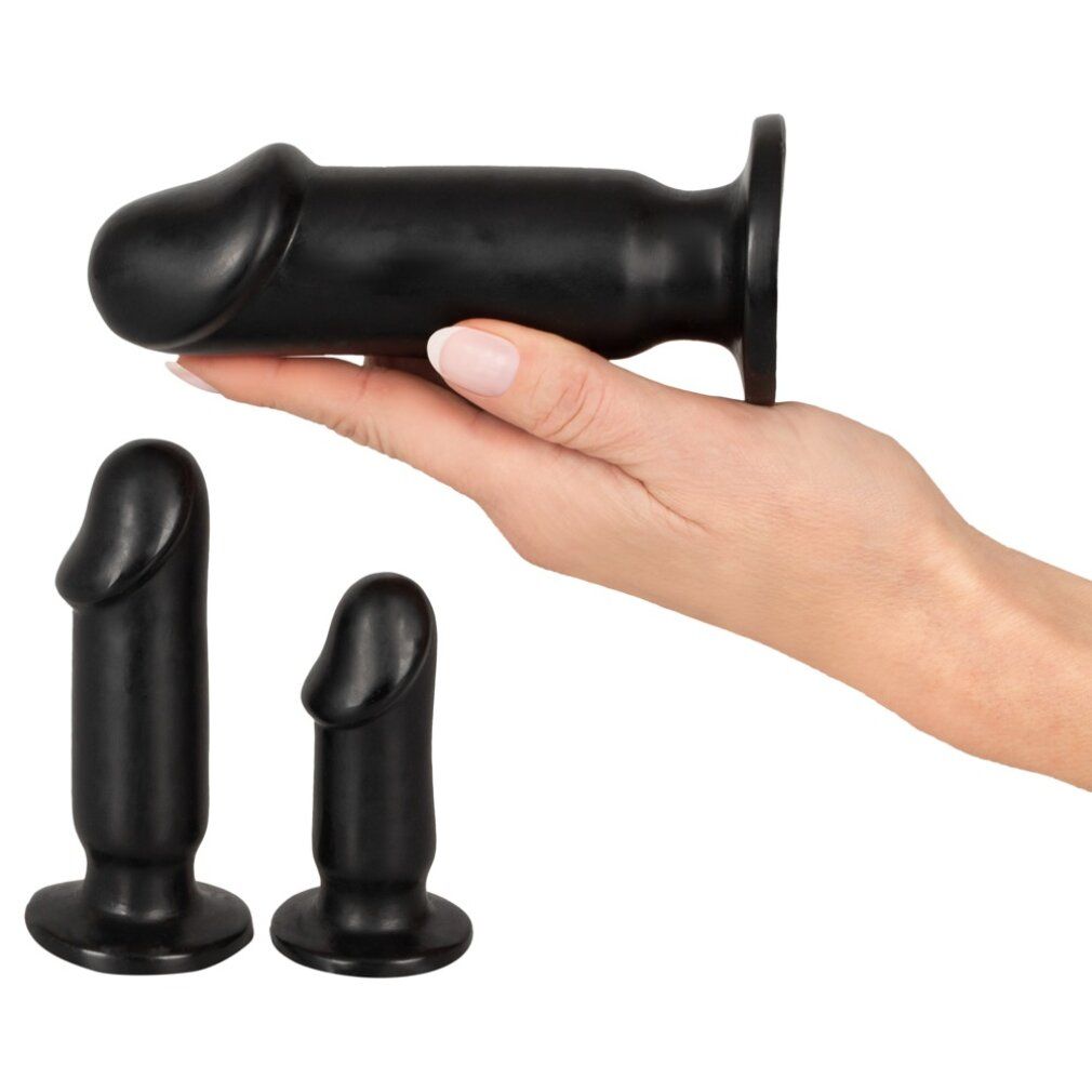 Tre plug anali neri. Un plug è tenuto in mano. Gli altri due sono accanto. Forma cilindrica con punta arrotondata.