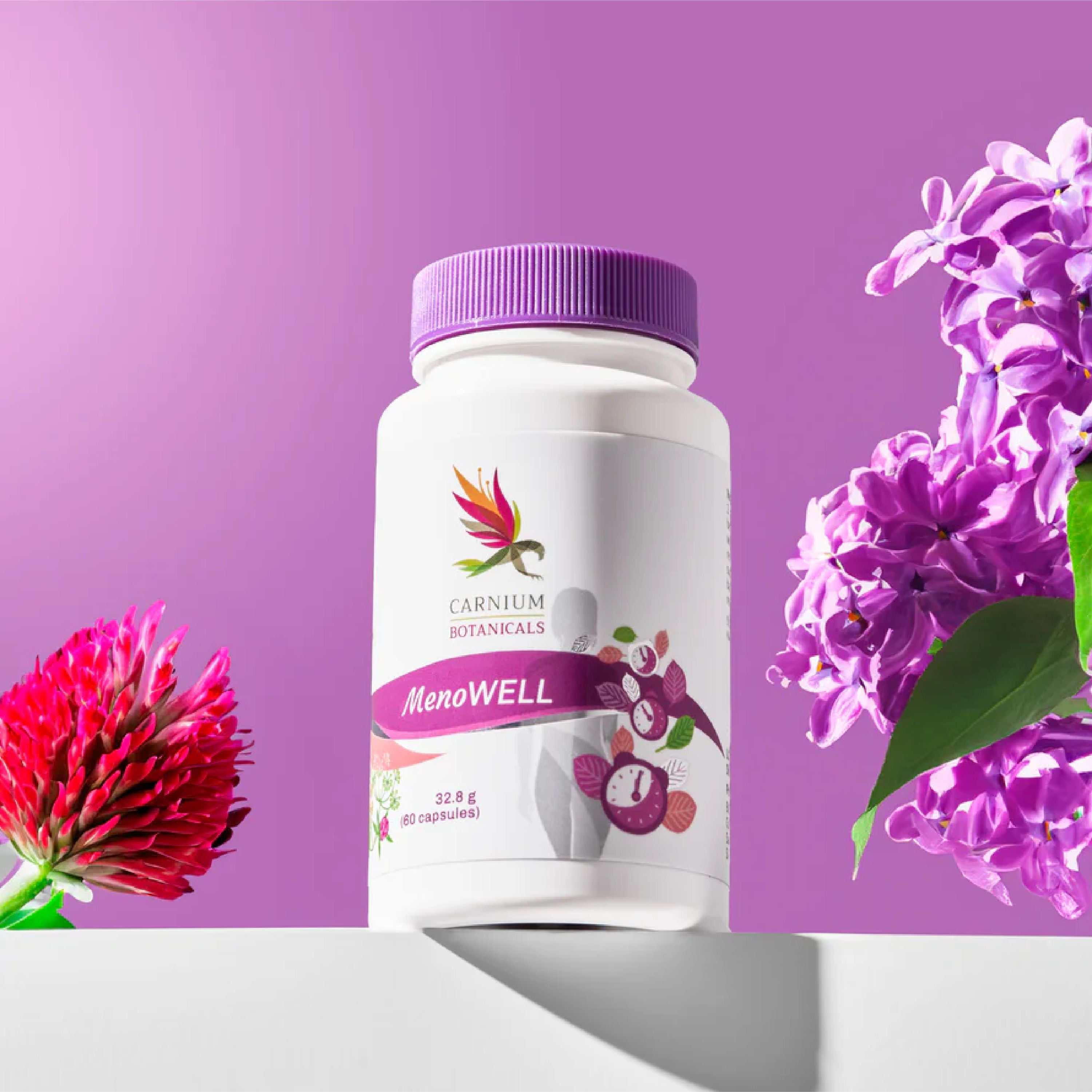 Barattolo di capsule Carnium Botanicals MenoWell su uno scaffale, circondato da fiori viola e rossi.