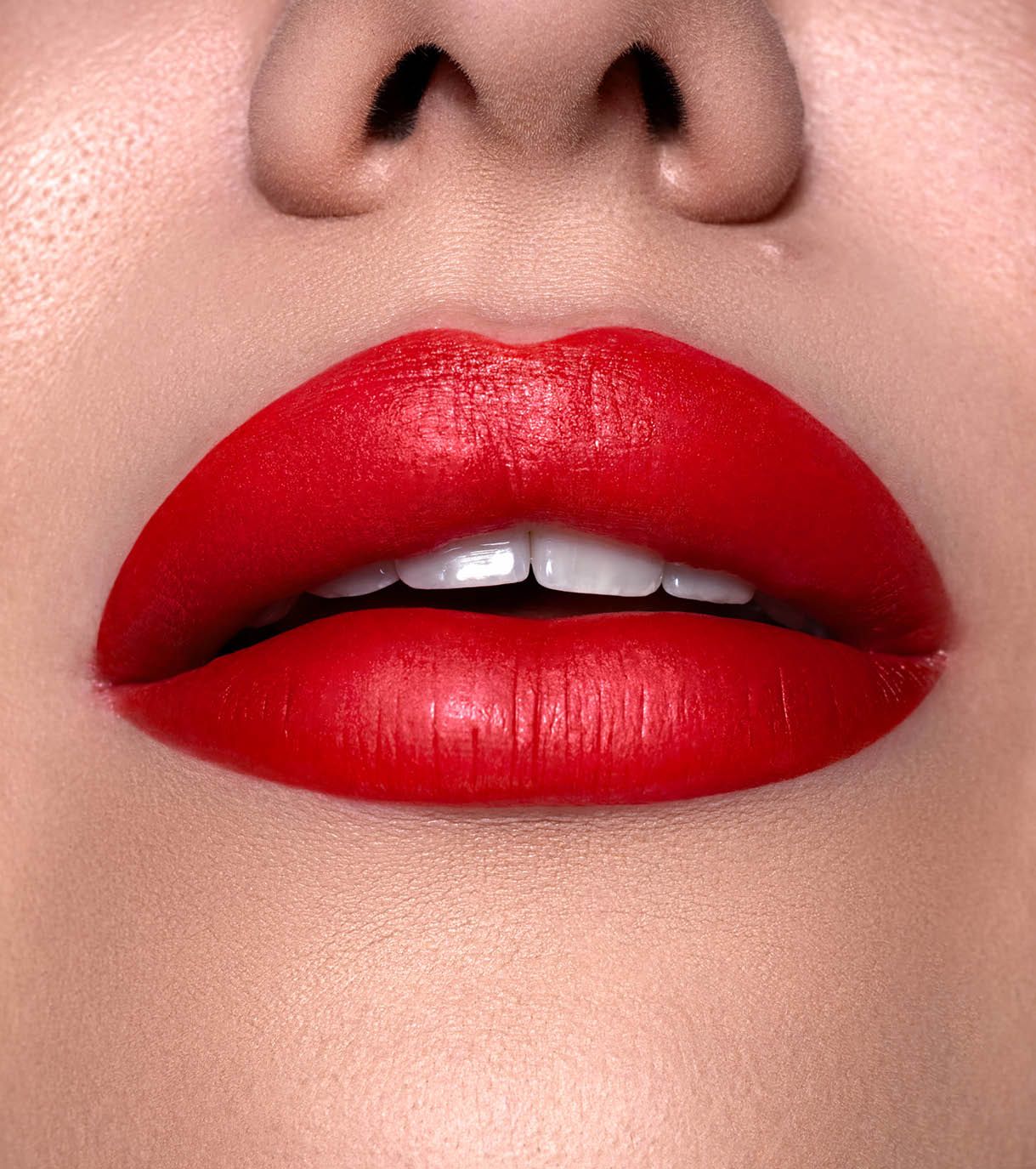 Primo piano di labbra carnose con rossetto rosso, denti visibili.