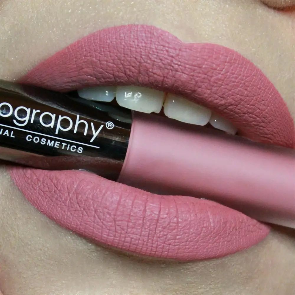 Labbra con rossetto liquido BODYOGRAPHY Lip Lava. Rossetto tra le labbra. Tonalità rosa. Tubo argentato con nome del marchio.