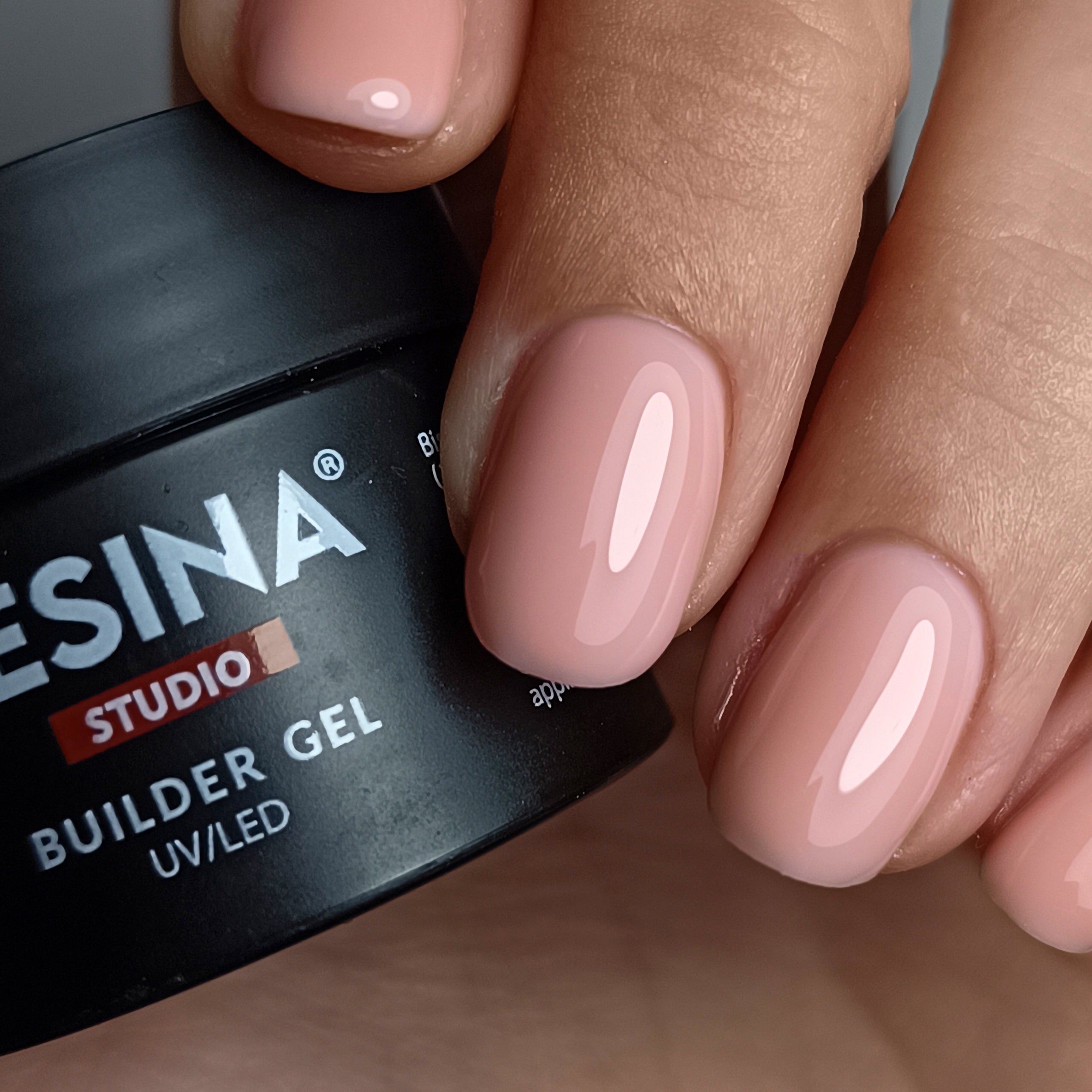 Mano con unghie smaltate rosa. Accanto, un vasetto nero con RESINA STUDIO e BUILDER GEL.