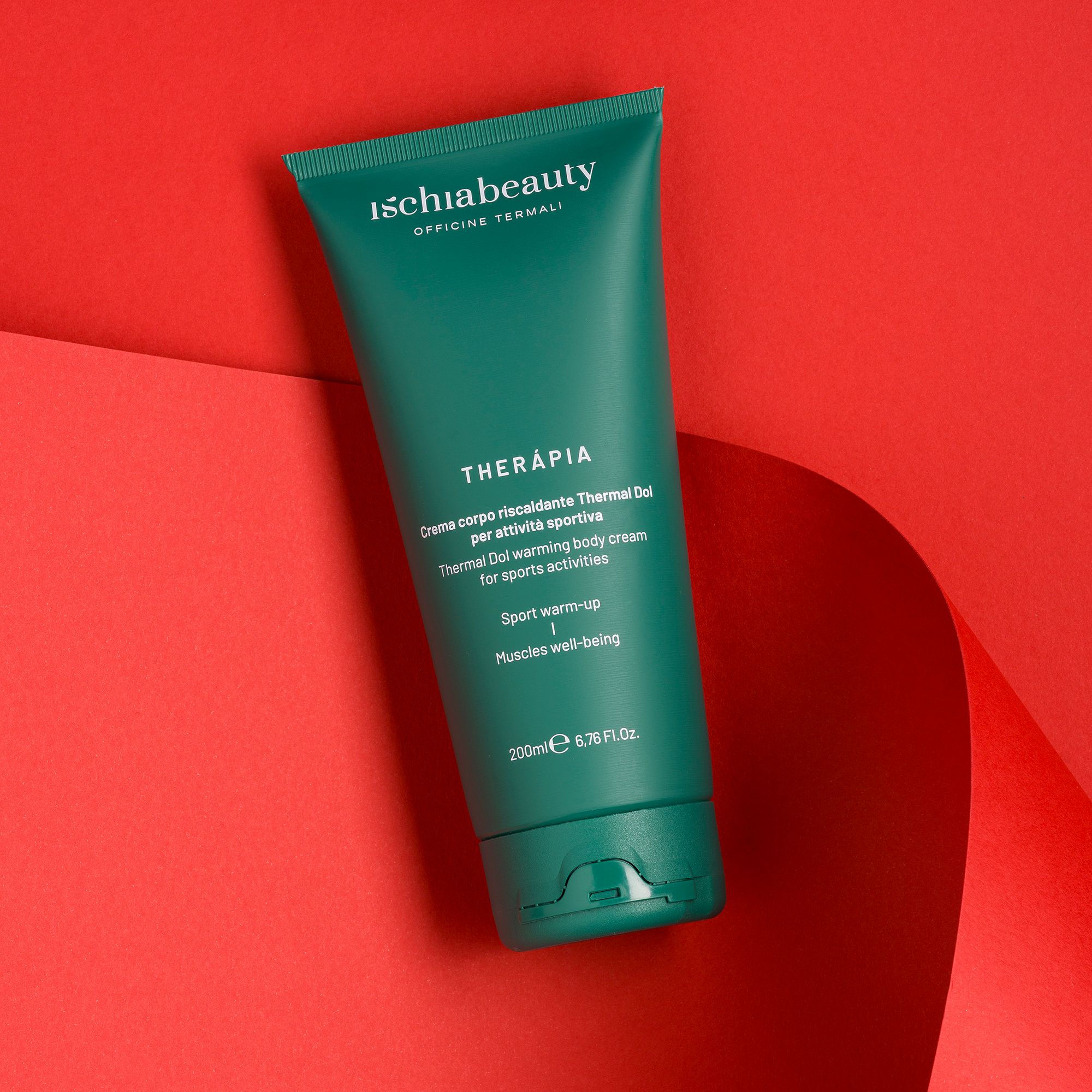 Tubo verde con testo. Ischiabeauty, THERAPIA, crema per sport. 200ml. Sfondo rosso.