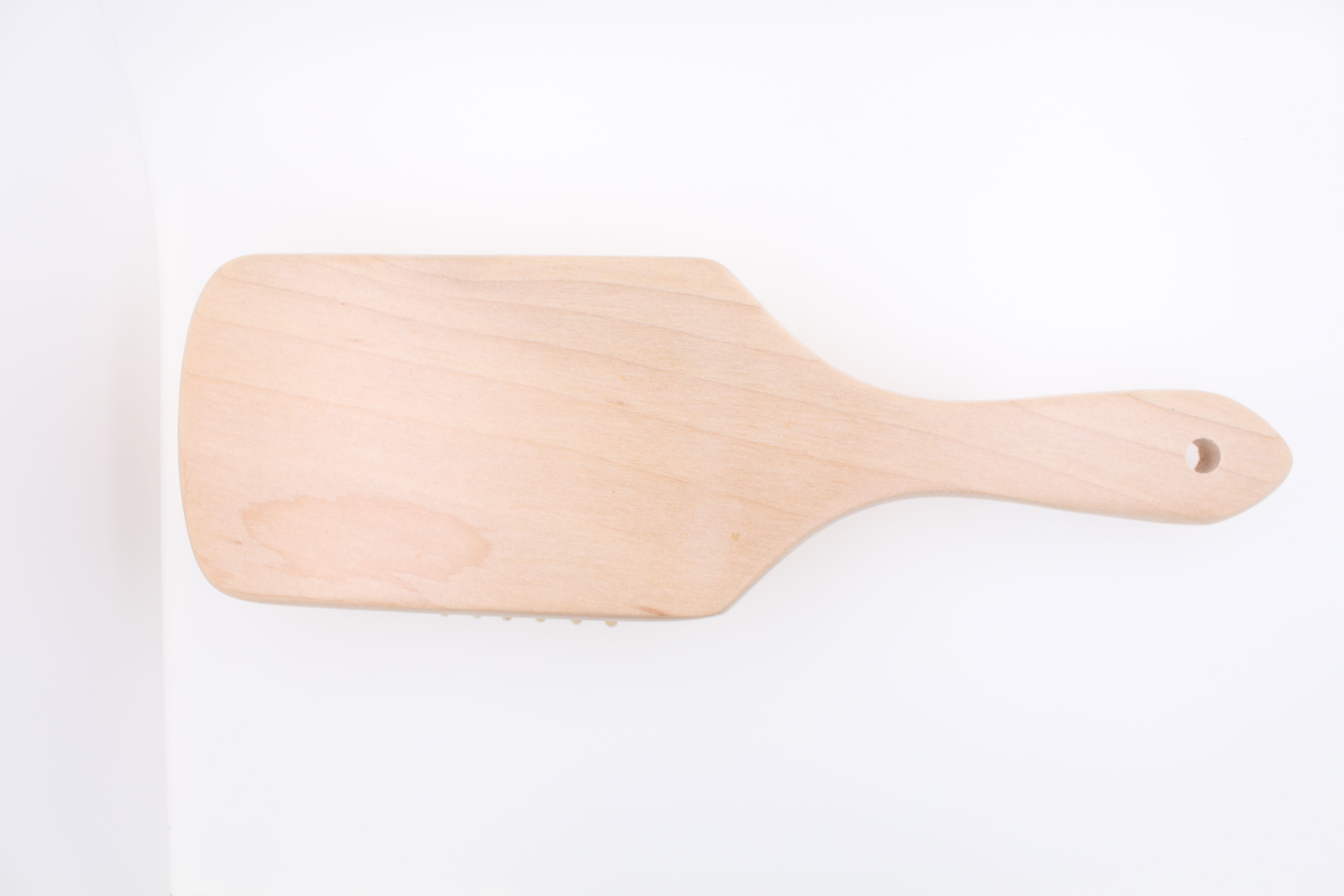 Retro di una spazzola per capelli in legno con testa rettangolare e manico, realizzata in legno chiaro.
