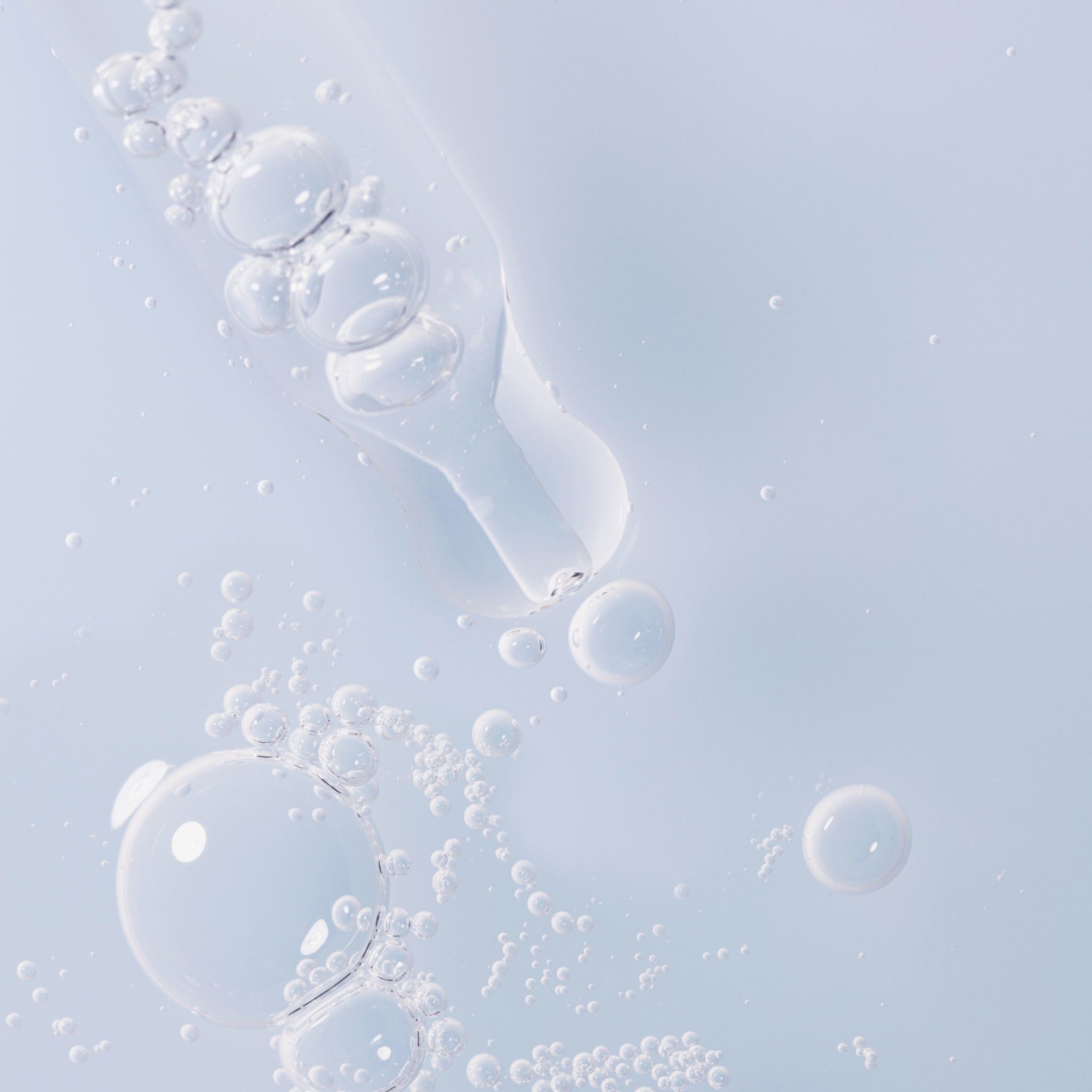 Primo piano di bolle di siero. Pipetta con goccioline di siero. Liquido blu chiaro.