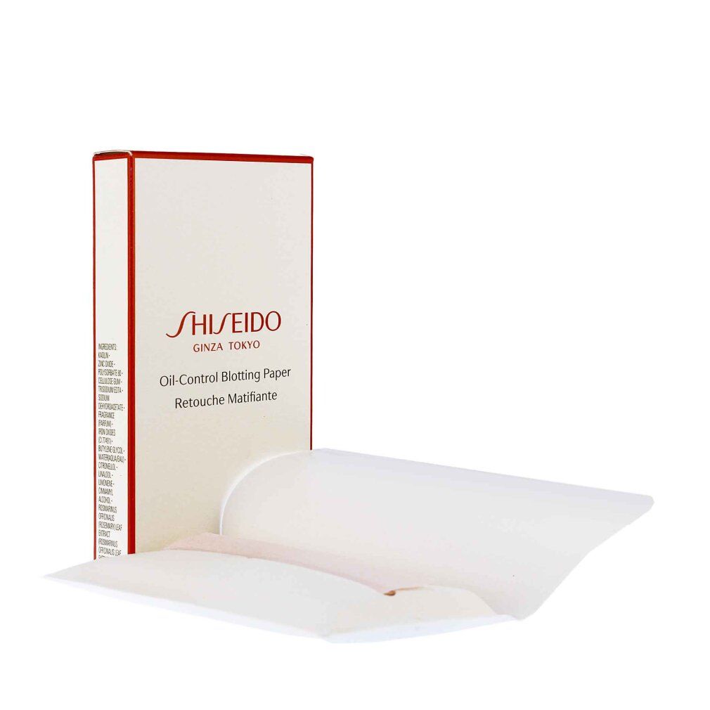 Fogli bianchi accanto a una scatola bianca con bordo rosso. Sulla scatola c'è Shiseido e Oil-Control Blotting Paper.