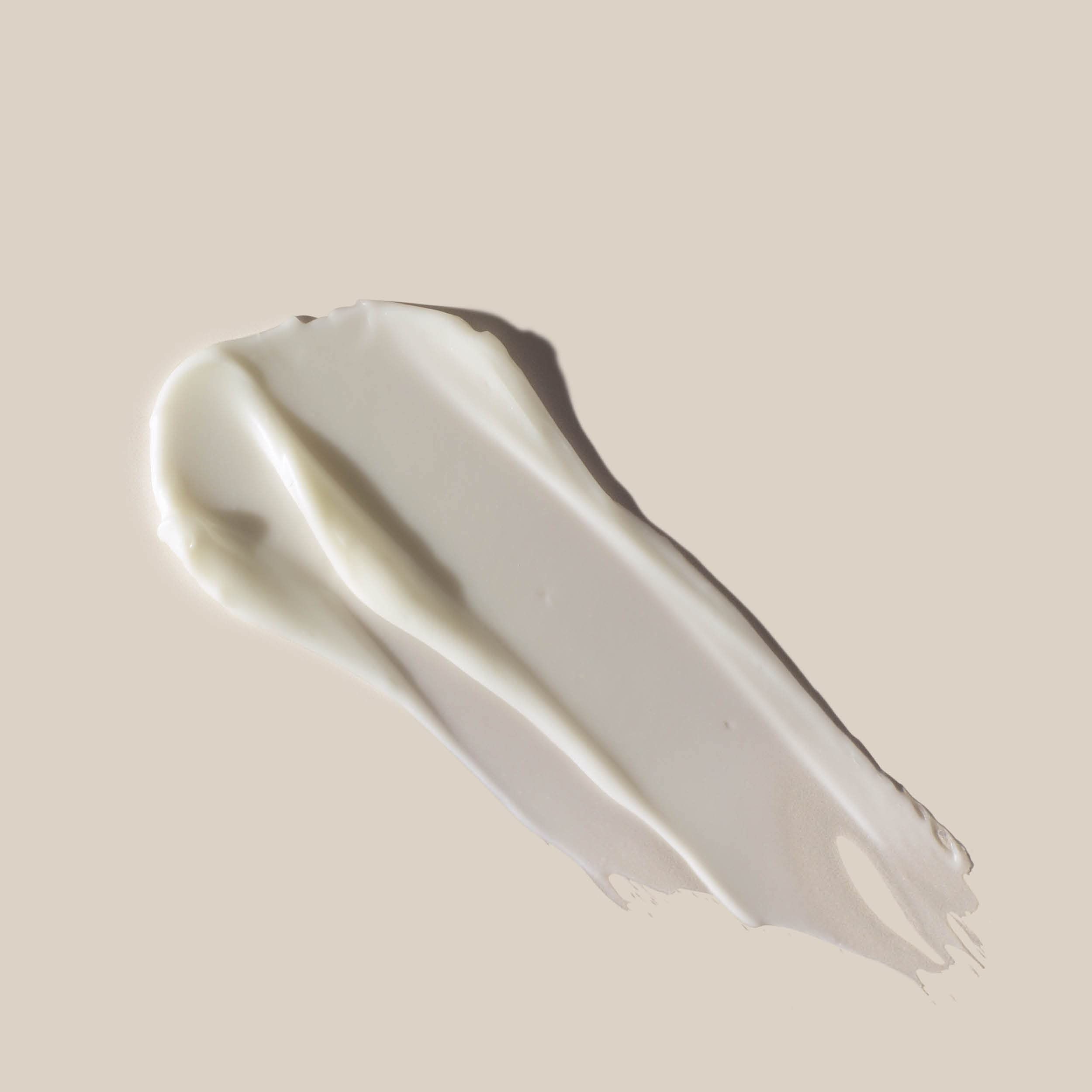 Striscio di crema su sfondo chiaro. Crema bianca dalla consistenza liscia. Forma: curva.