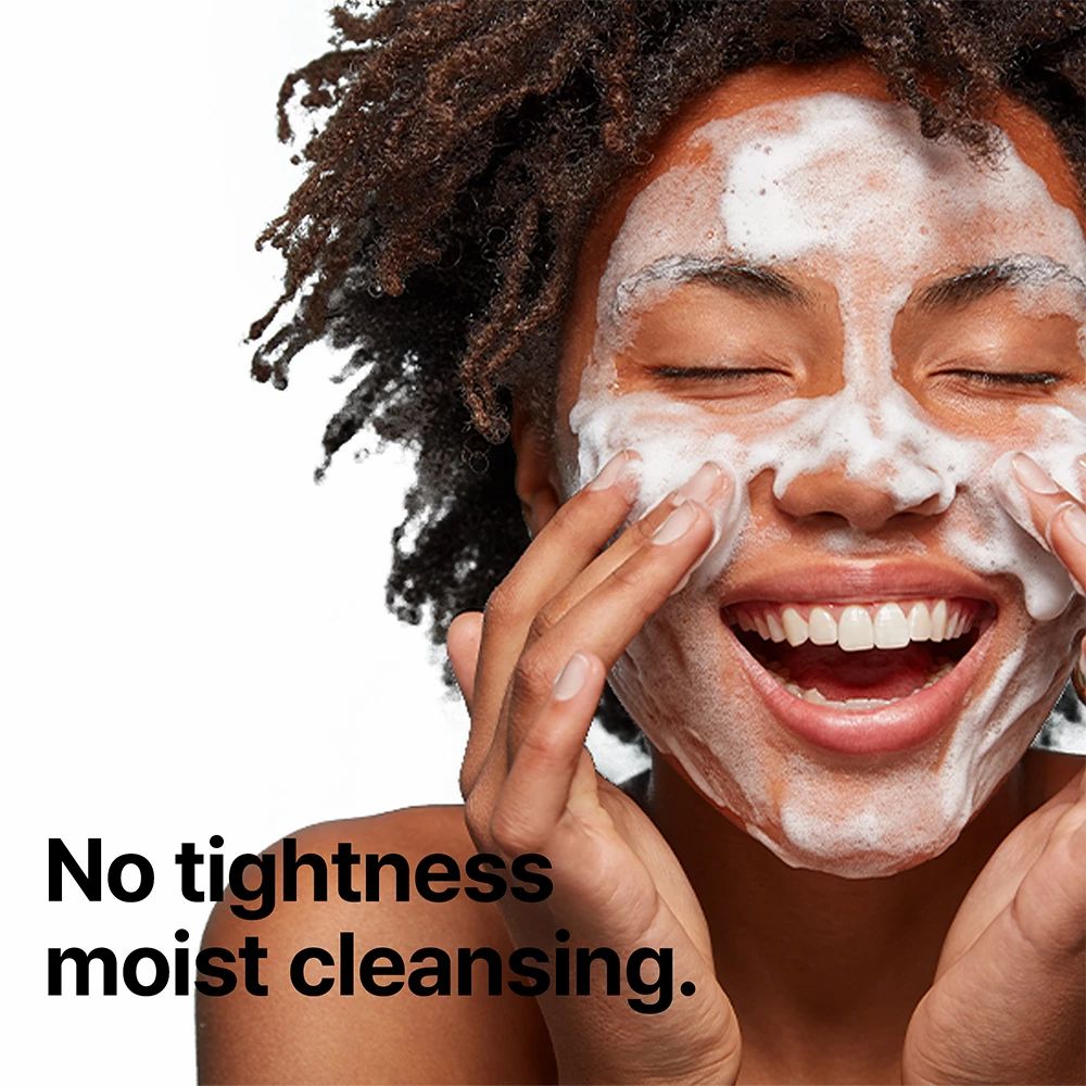 Una donna con gli occhi chiusi e schiuma sul viso. Testo: No tightness moist cleansing.