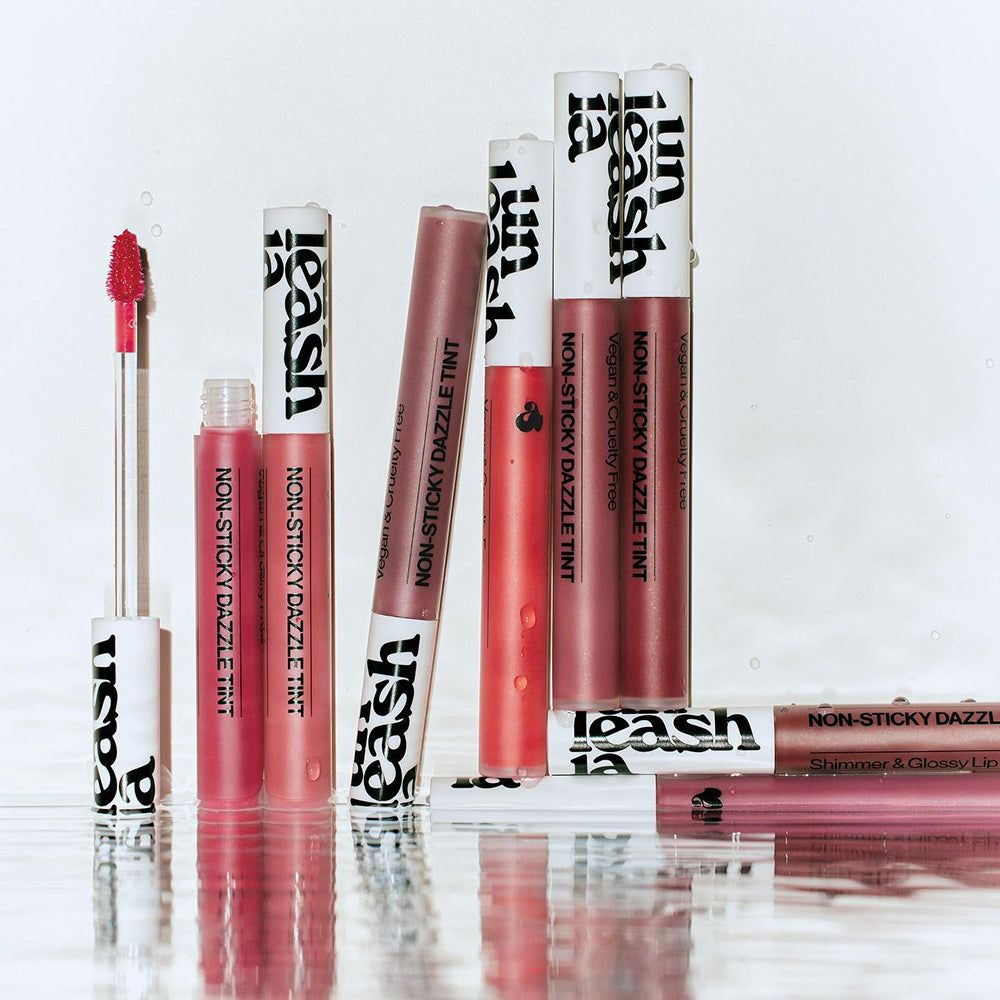 Diversi tubetti di lucidalabbra con tappo bianco e scritta nera. Scritta: Non-Sticky Dazzle Tint.