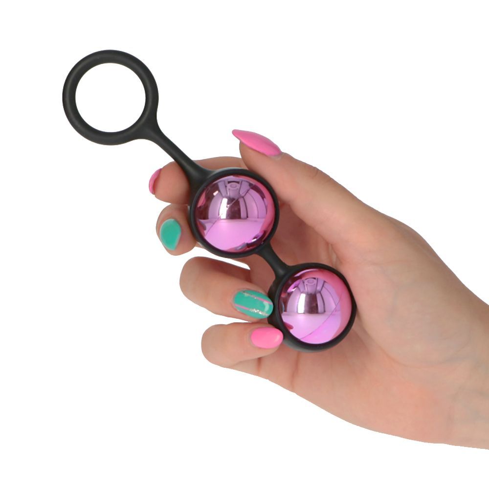 Due sfere rosa collegate con anello nero, tenute in mano con unghie colorate.