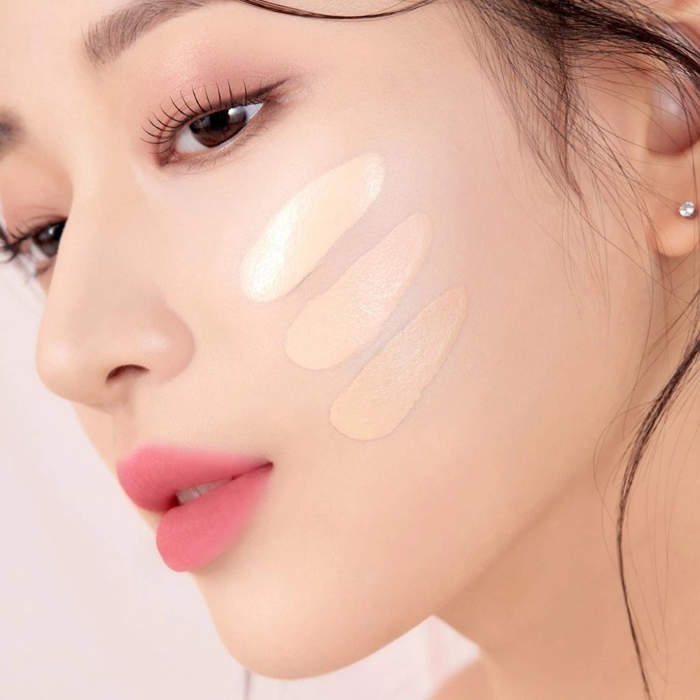 Primo piano di una donna con tre tonalità di BLACK ROUGE Thin Layer Velour Cushion Foundation sulla guancia.