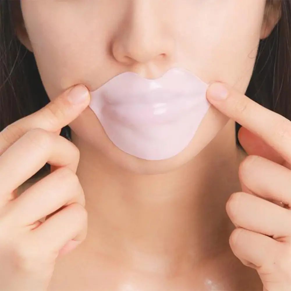 Maschera per labbra in idrogel sulle labbra. Pelle chiara, mani che tengono la maschera. Maschera labbra rosa a forma di labbra.