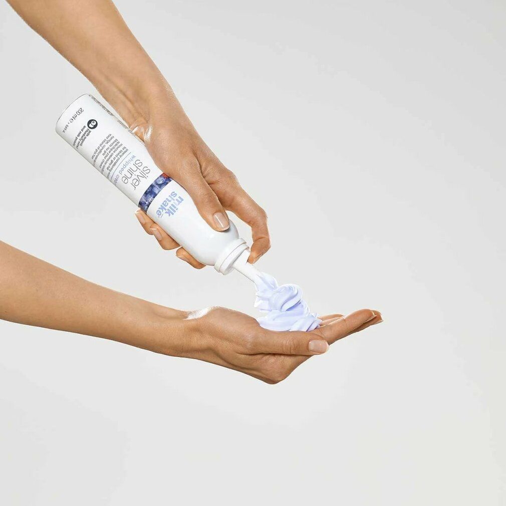 Mani che tengono flacone bianco "silver shine whipped cream" e applicano crema. Nome del prodotto visibile.