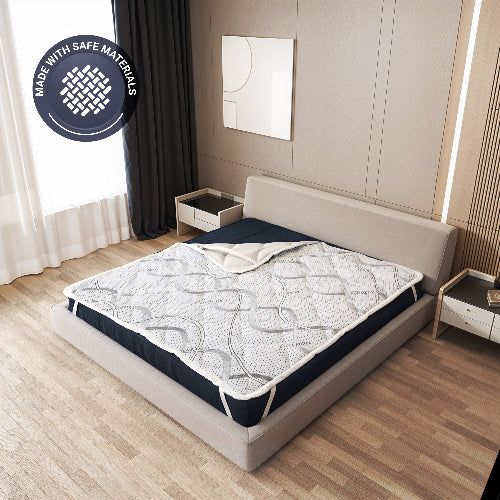 Coprimaterasso su un letto in camera da letto, con sigillo 'Realizzato con materiali sicuri'.
