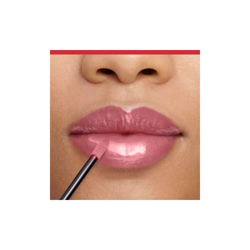 Primo piano di labbra con lucidalabbra rosa applicato. Applicatore in uso. Finitura lucida.