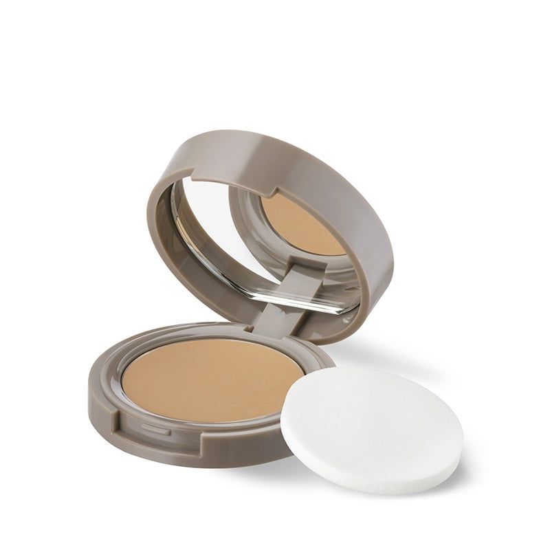 Correttore compatto beige con specchio e spugnetta. Confezione rotonda beige aperta.