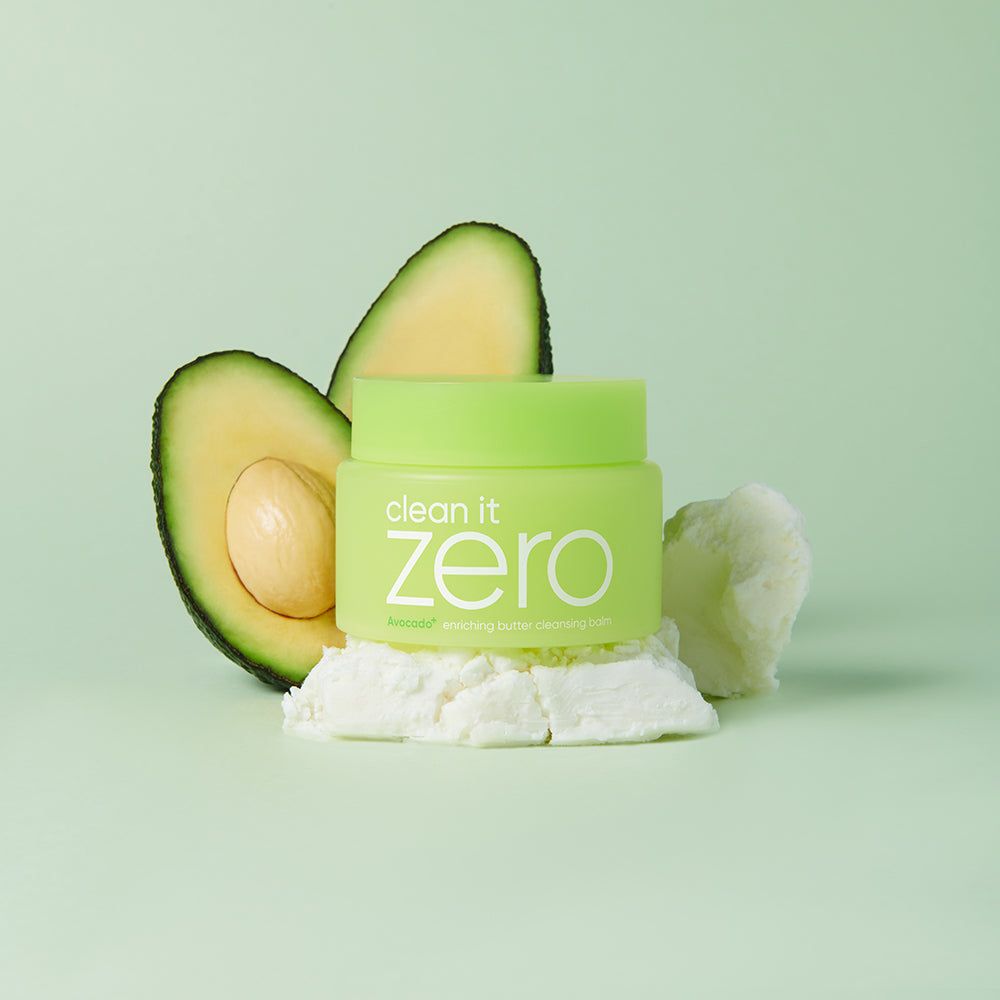 Contenitore verde accanto a fette di avocado e burro bianco su sfondo chiaro.
