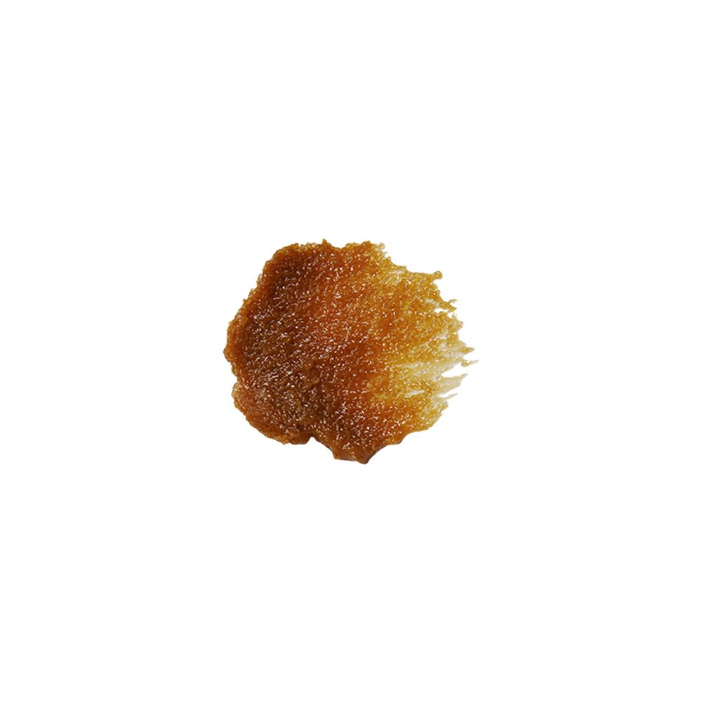 Una piccola quantità di Klairs Gentle Black Sugar Facial Polish come mucchio di granuli marroni.