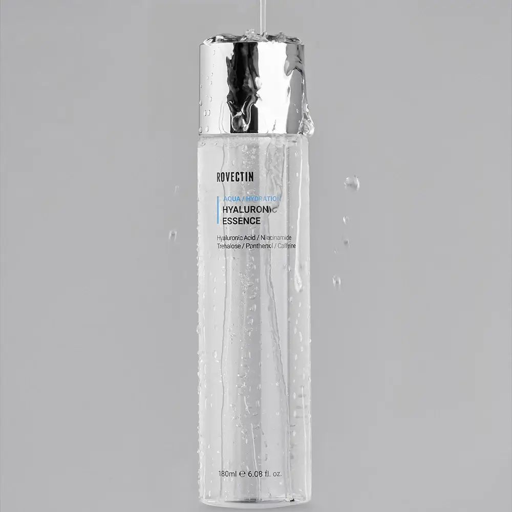 Flacone ROVECTIN AQUA/HYDRATION HYALURONIC ESSENCE con gocce d'acqua. Tappo argentato. Sfondo grigio.