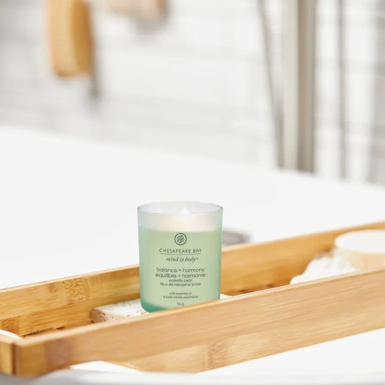 Candela in contenitore di vetro. Scritta: Chesapeake Bay, mind & body, balance + harmony, équilibre + harmonie. Su vassoio di legno.