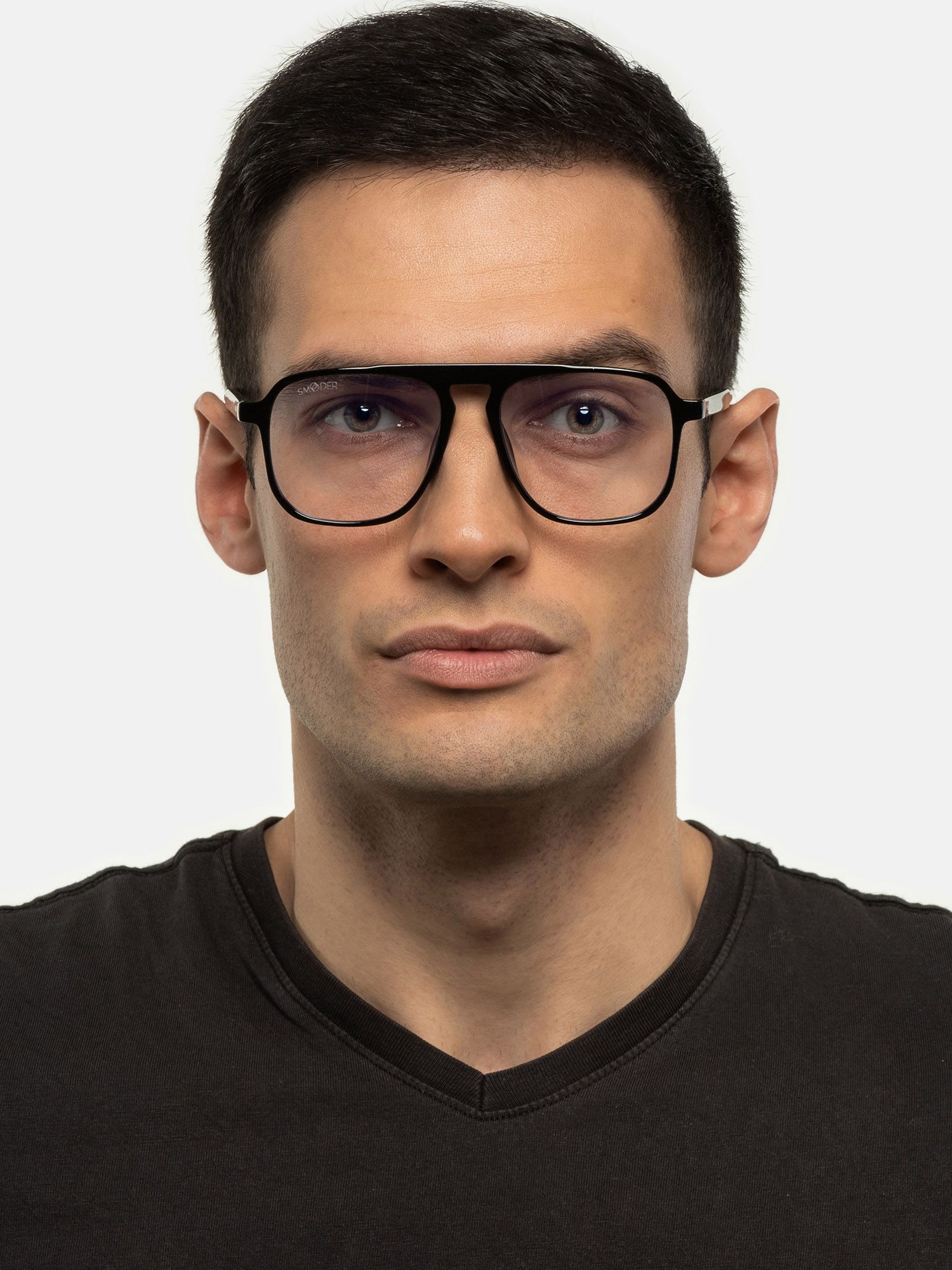 Uomo con occhiali neri. Lenti quadrate, barra superiore. Il logo 'SMOODER' è visibile sulla lente sinistra.