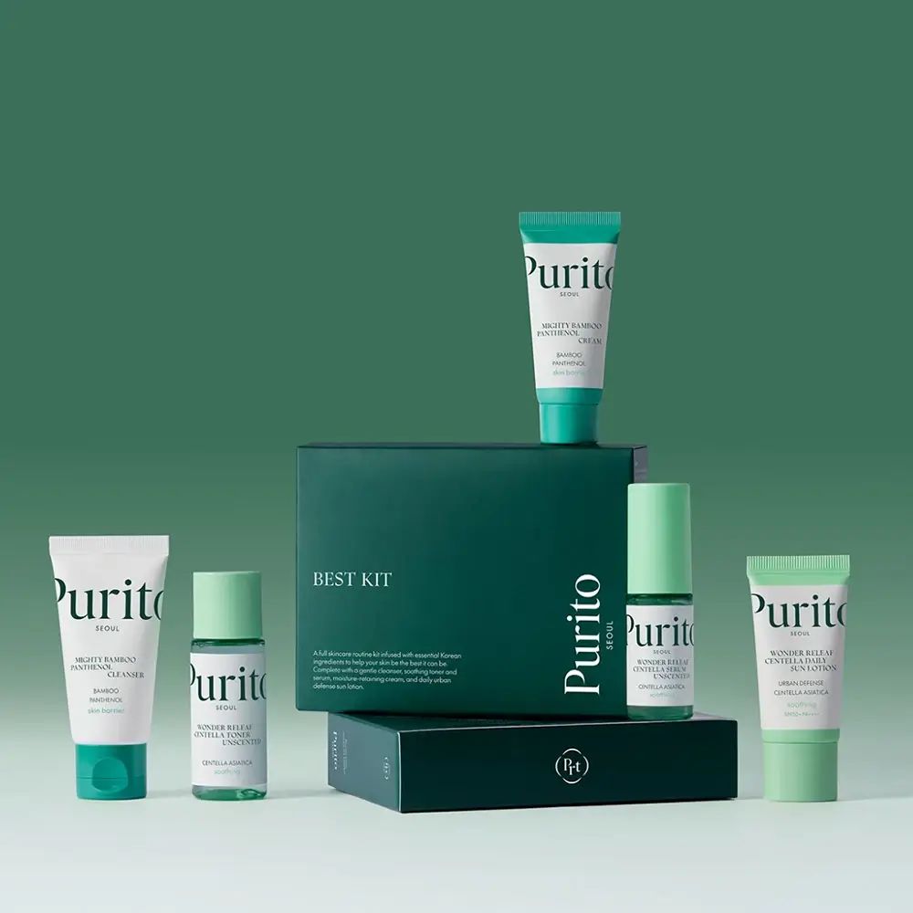 Vari prodotti per la cura della pelle in formato da viaggio. Tubi e flaconi verde e bianchi, disposti davanti a una scatola verde con "BEST KIT".