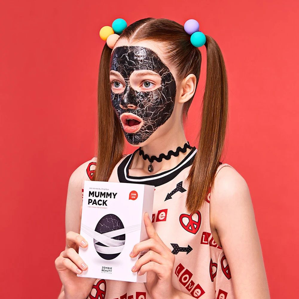 Persona con maschera viso e scatola bianca con scritta MUMMY PACK.