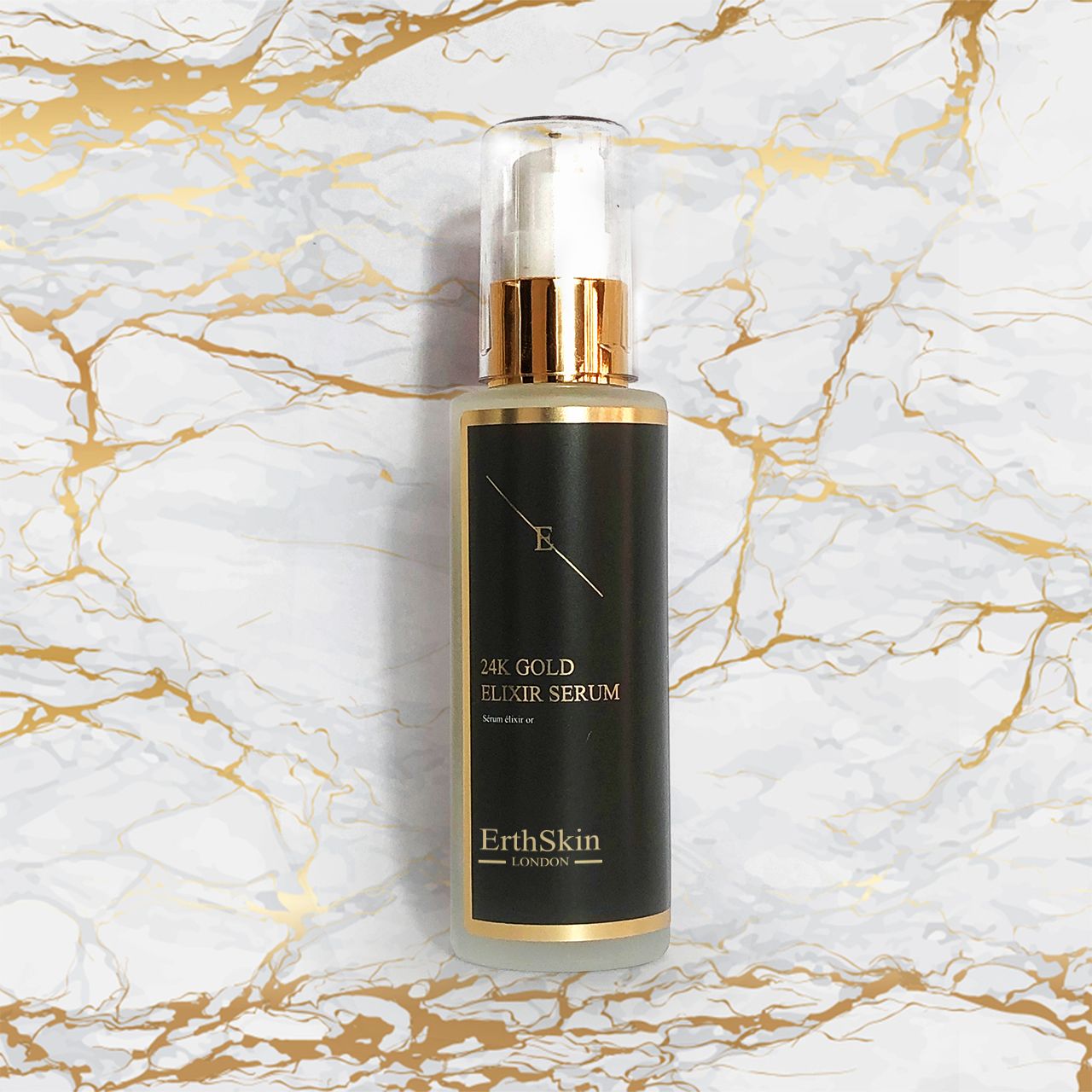 Flacone di siero con etichetta nera e dettagli dorati. Su sfondo marmoreo. Scritta: 24K Gold Elixir Serum.