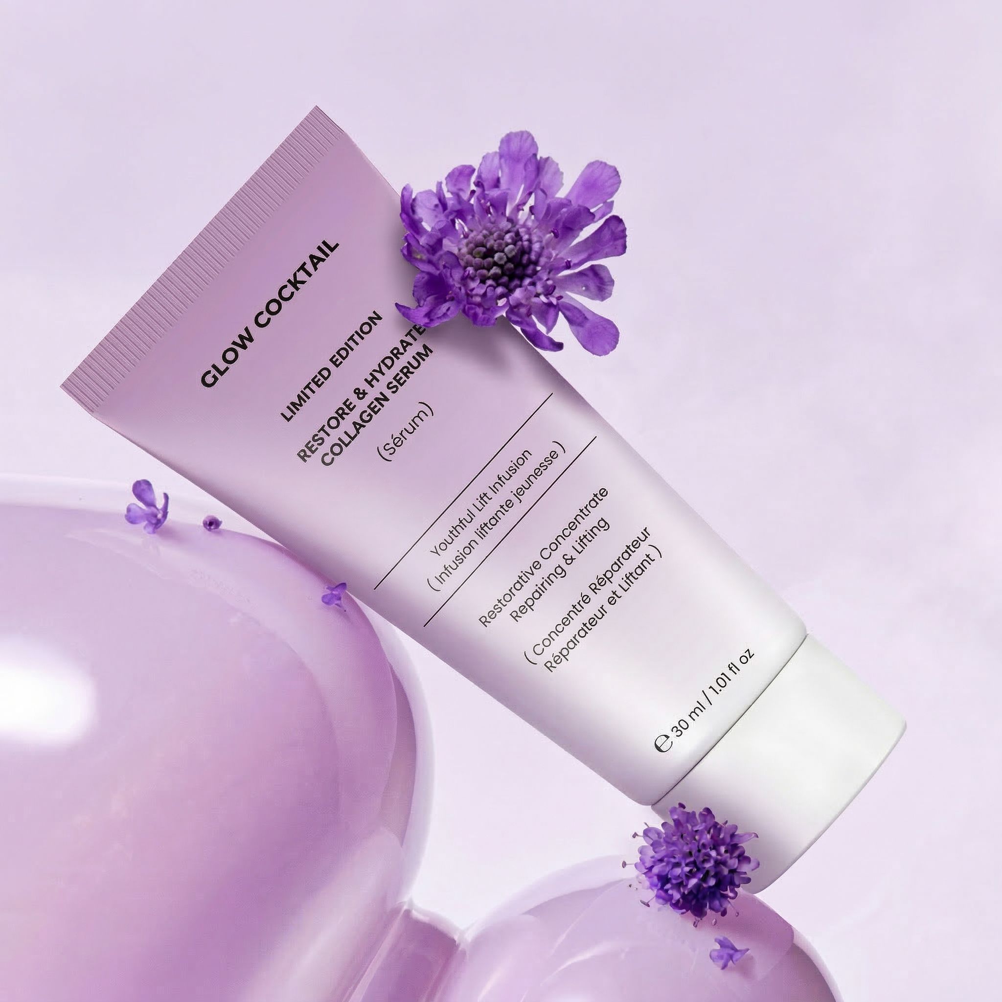 Un tubetto viola chiaro con la scritta "Glow Cocktail Restore & Hydrate Collagen Serum", con fiori viola e bolle.