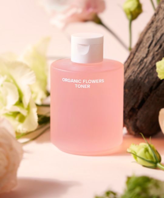 Flacone rosa con tappo bianco, circondato da fiori. Scritta: ORGANIC FLOWERS TONER.