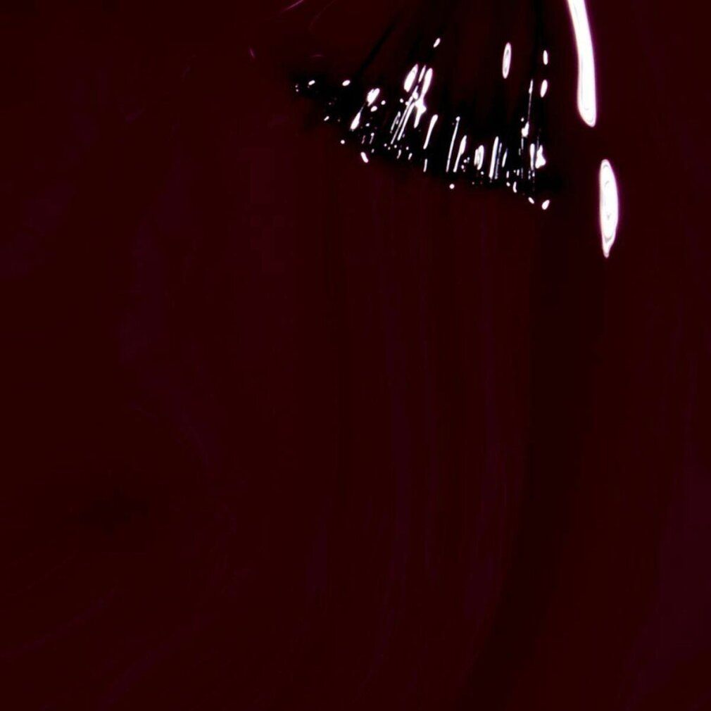 Primo piano di un pennello con smalto per unghie. Smalto rosso scuro, setole bianche.