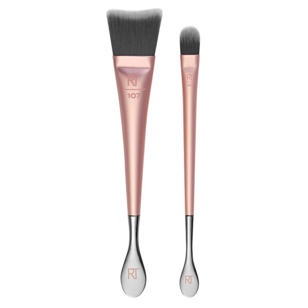 Pennello trucco doppio con manici color oro rosa e setole grigie. Un pennello è piatto e largo, l'altro stretto e ovale.