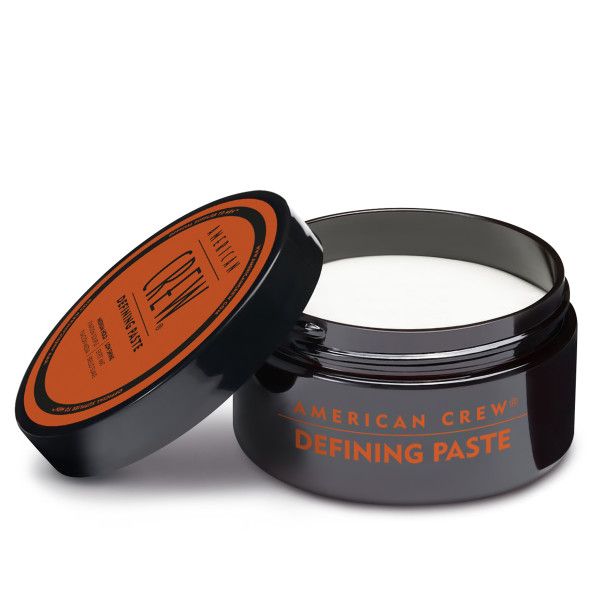 Barattolo di AMERICAN CREW Defining Paste aperto. Barattolo nero, etichetta arancione. Testo: Defining Paste.