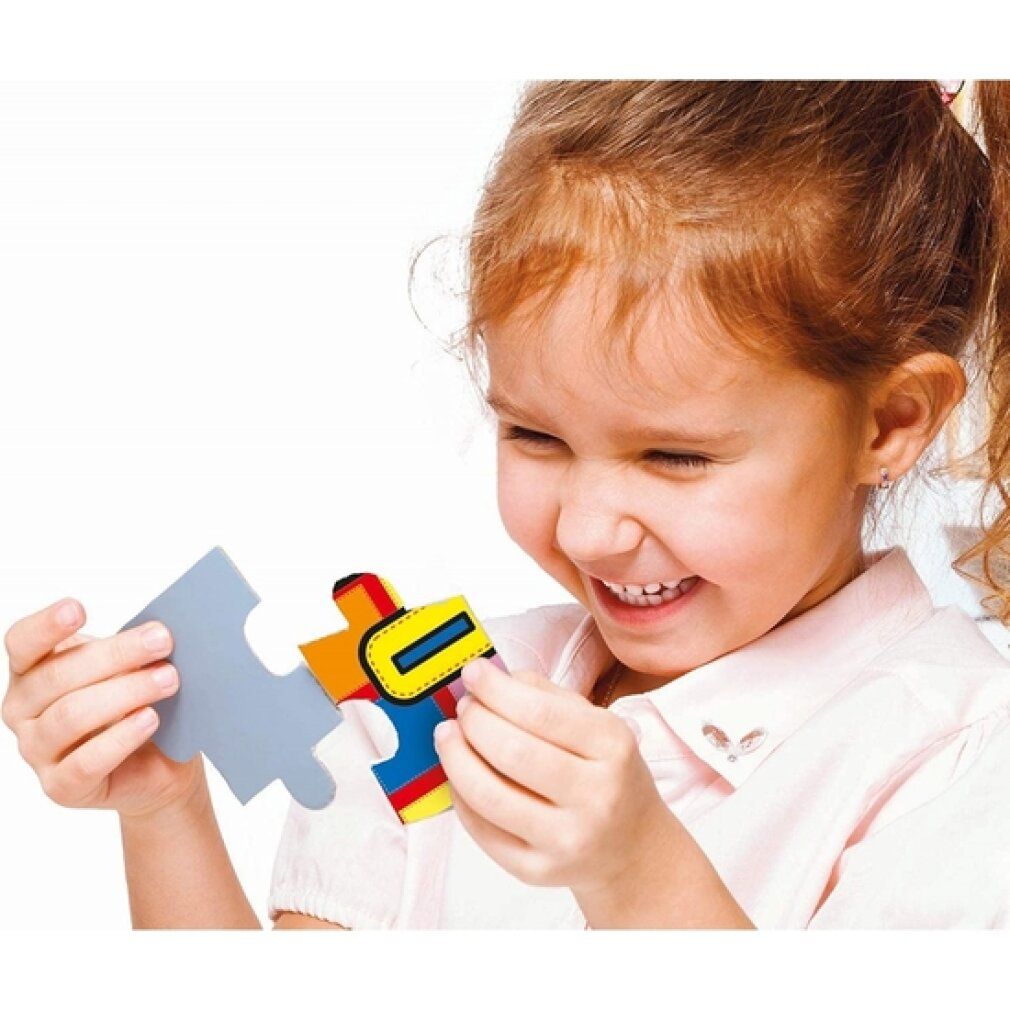 Bambino tiene un pezzo di puzzle. Pezzo di puzzle con elementi gialli, rossi, blu e verdi. Il bambino sorride. Sfondo bianco.