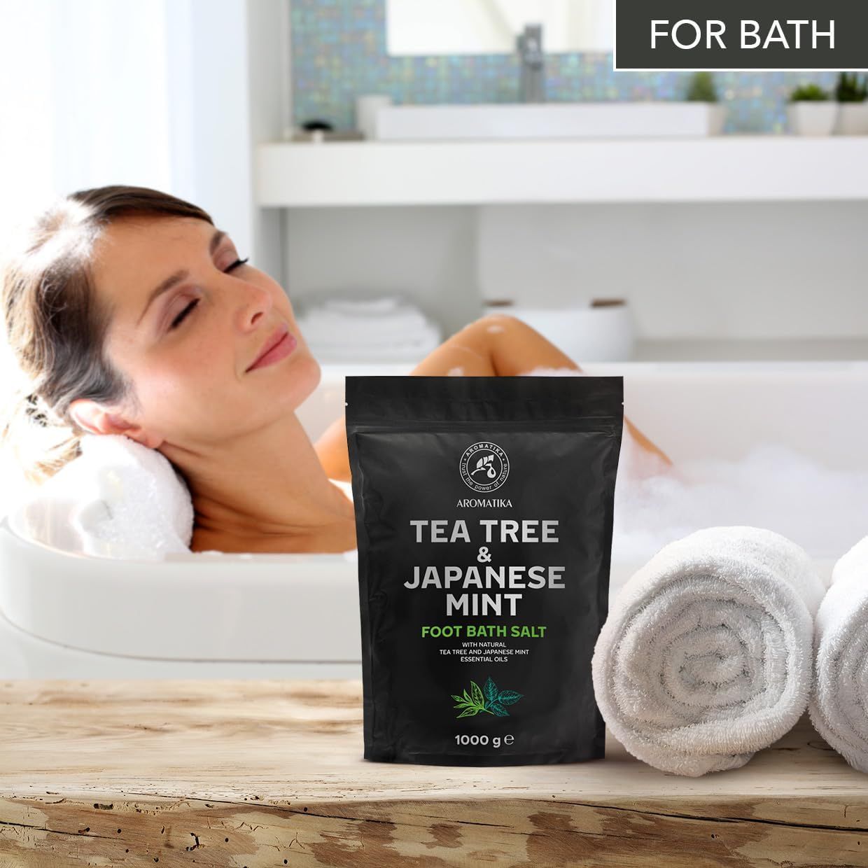 Donna in bagno. Confezione nera accanto agli asciugamani. Testo: 'For bath'.