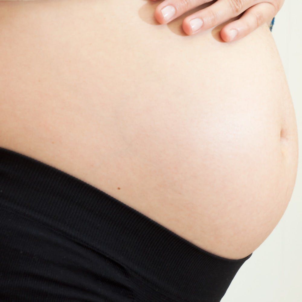 Tessuto nero sull'addome. Donna incinta, primo piano del ventre.