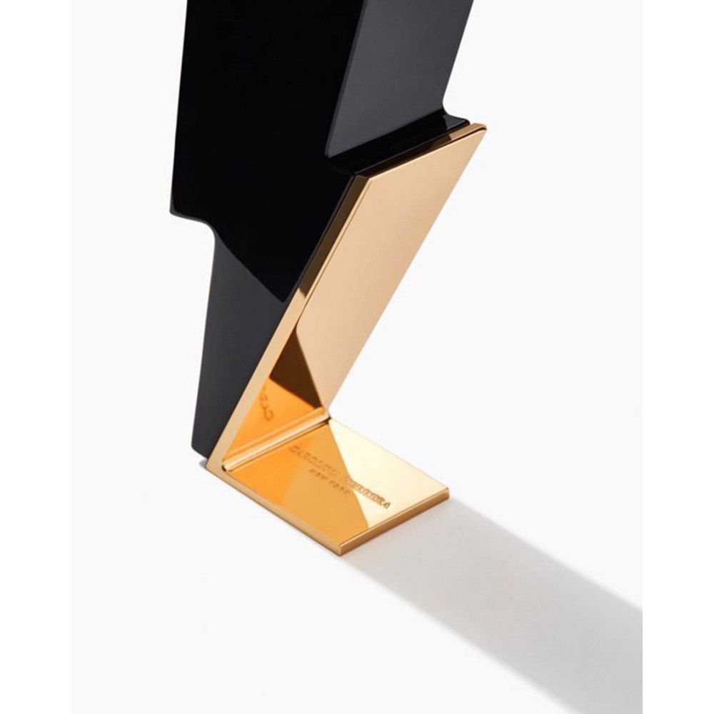 Flacone nero a forma di fulmine con base dorata. Scritta sulla base.