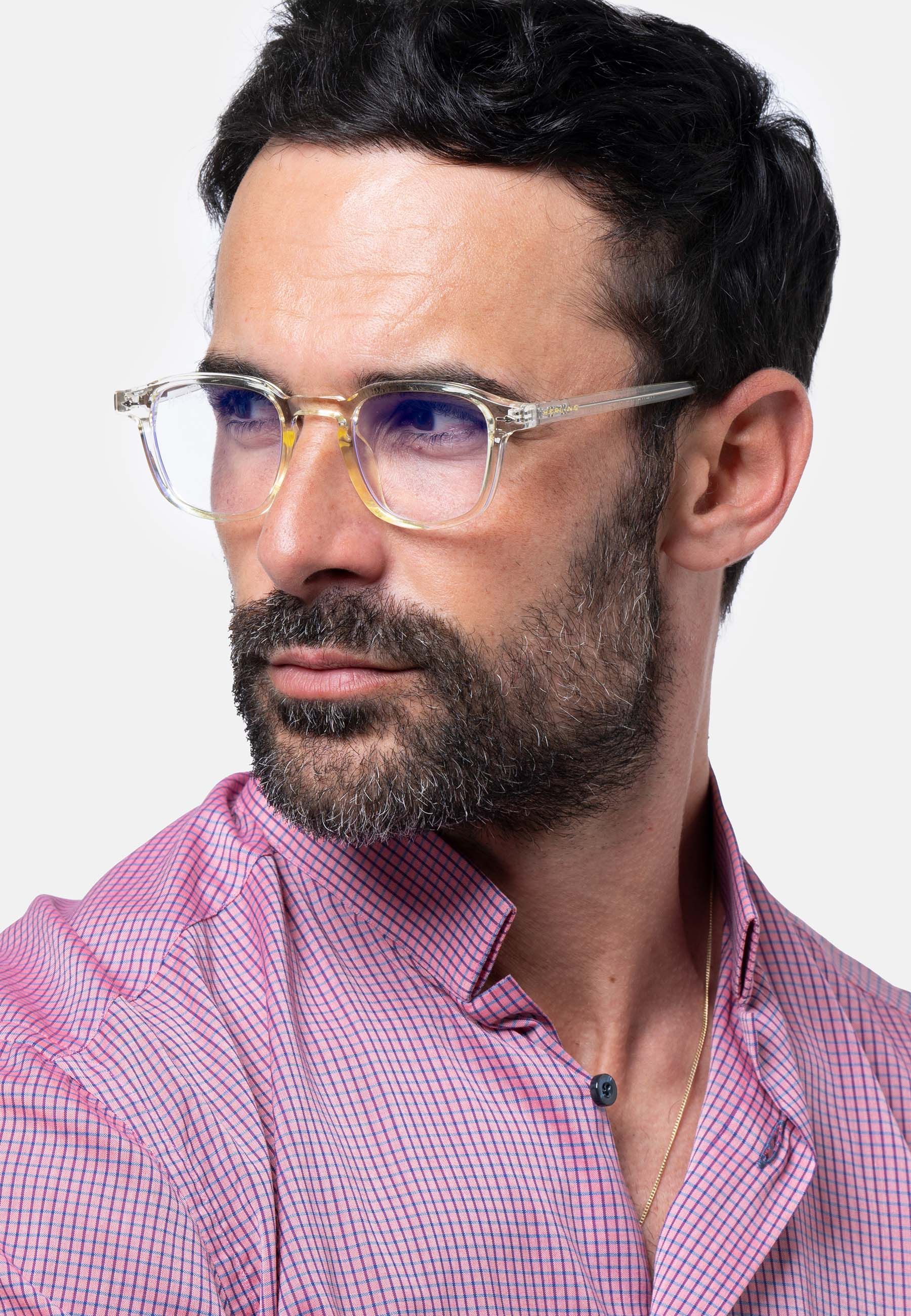 Uomo con occhiali trasparenti. Dettagli gialli. Logo Herling visibile. Camicia rosa.