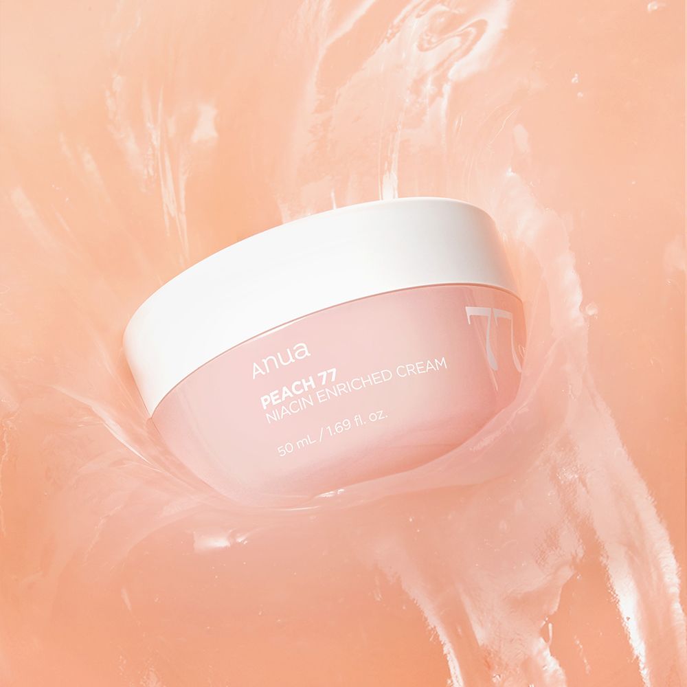 Crema arricchita alla niacinamide ANUA Peach 77% in un vasetto rosa, posizionata in un liquido cremoso color pesca.