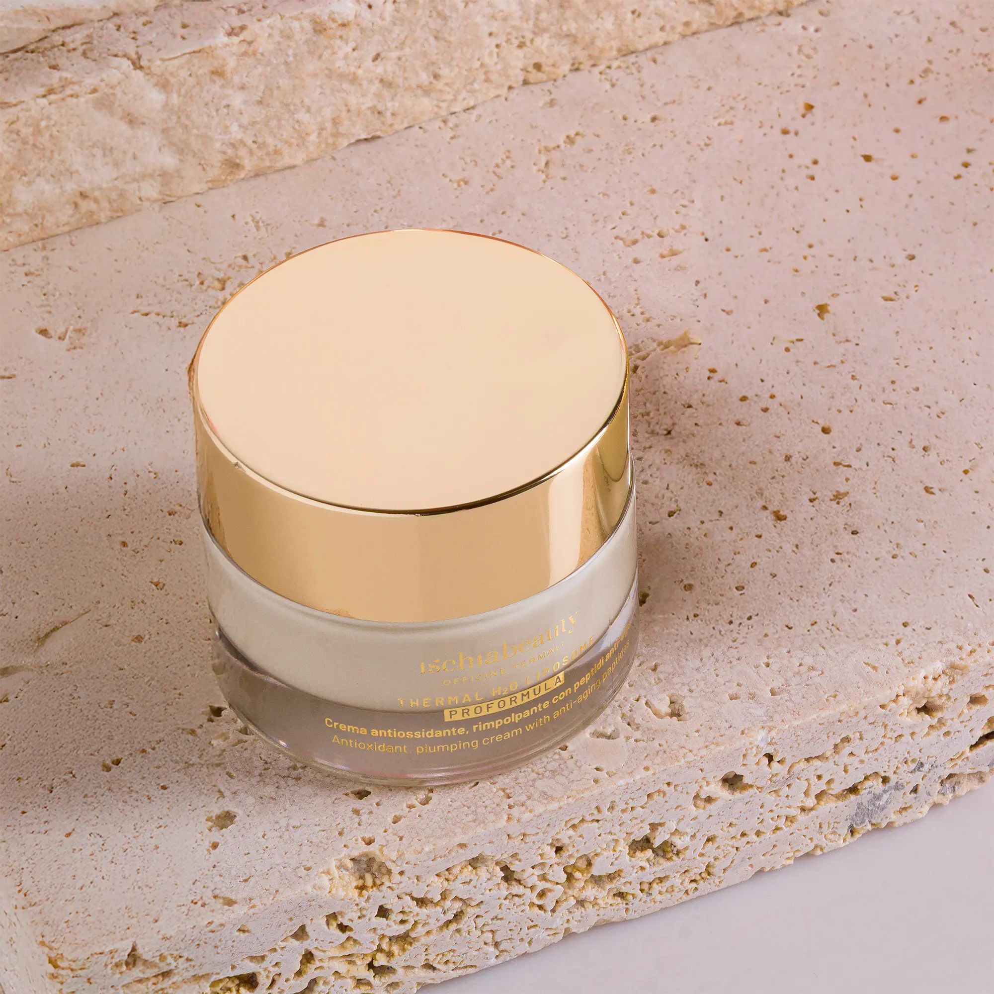 Vasetto di crema con coperchio dorato. Su lastra di pietra. Scritta del prodotto visibile. Contenitore trasparente.