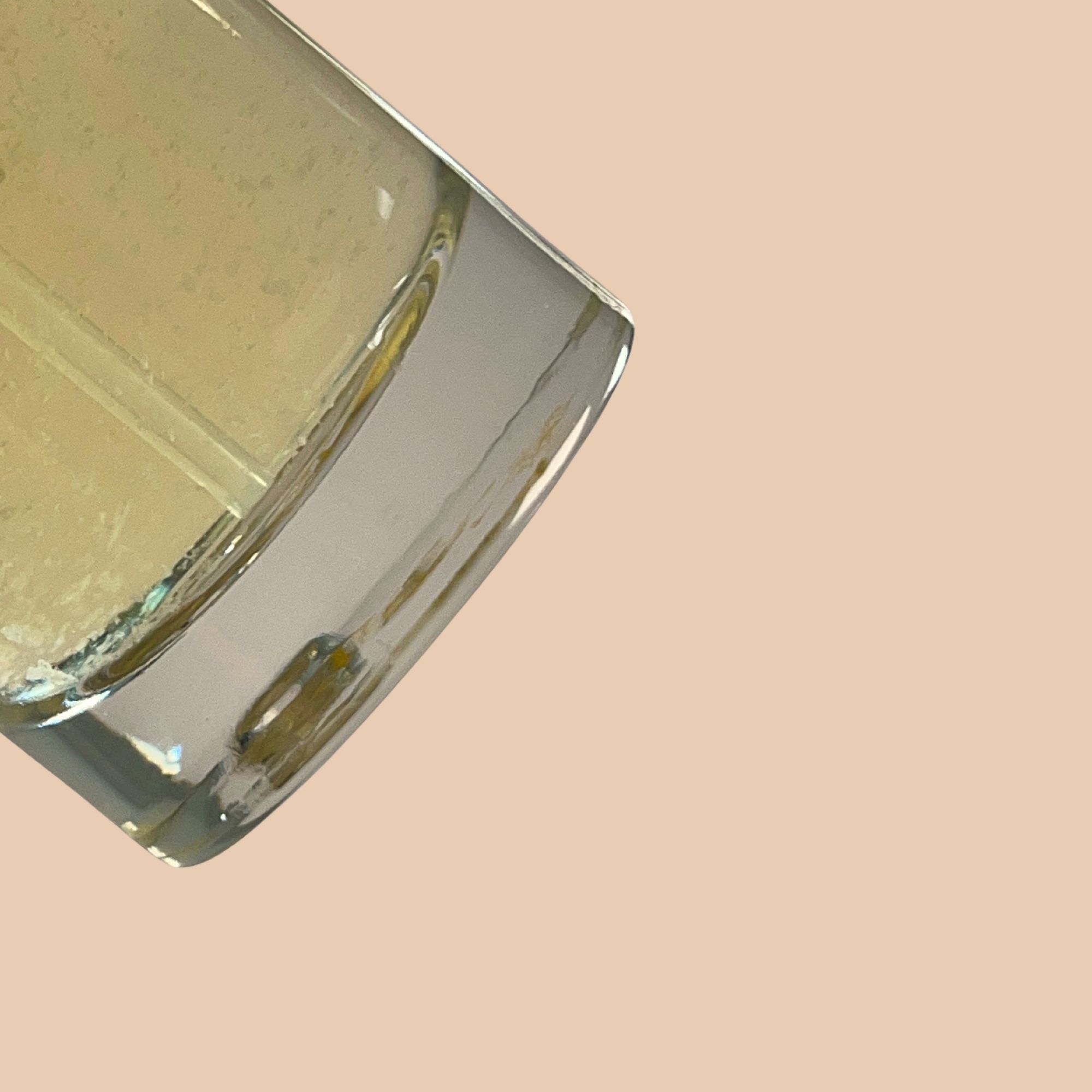 Primo piano di un flacone in vetro. Liquido di colore giallastro. Forma rettangolare con bordi arrotondati.