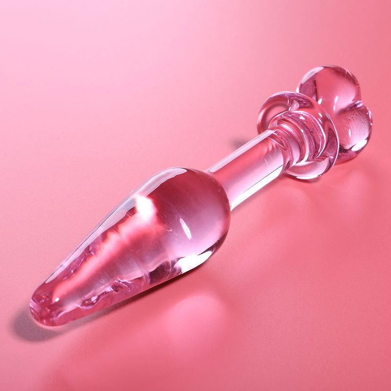 Spina anale in vetro rosa a forma di cuore, su sfondo rosa.