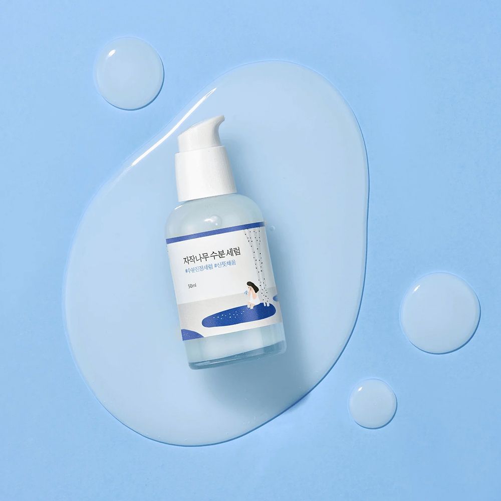 Round Lab Birch Juice Serum, 50ml, su una macchia di gel blu con gocce. Flacone con erogatore.